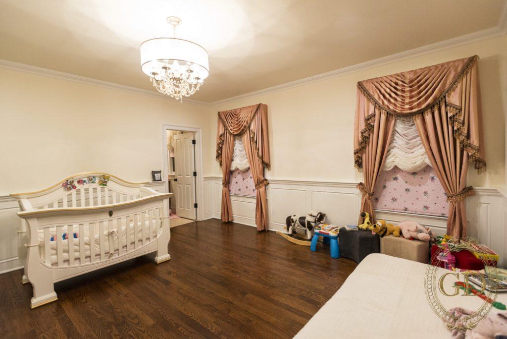 a baby's room with a crib and blinds drawn down on two draped windows