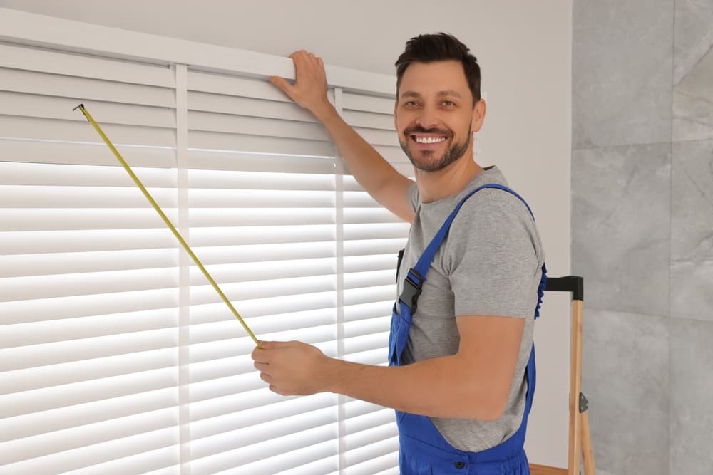 Worker in uniform measuring out the window blinds