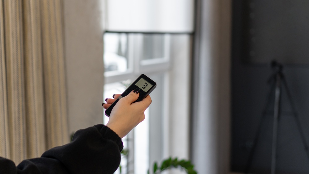 Woman using a remote control to adjust motorized window shades