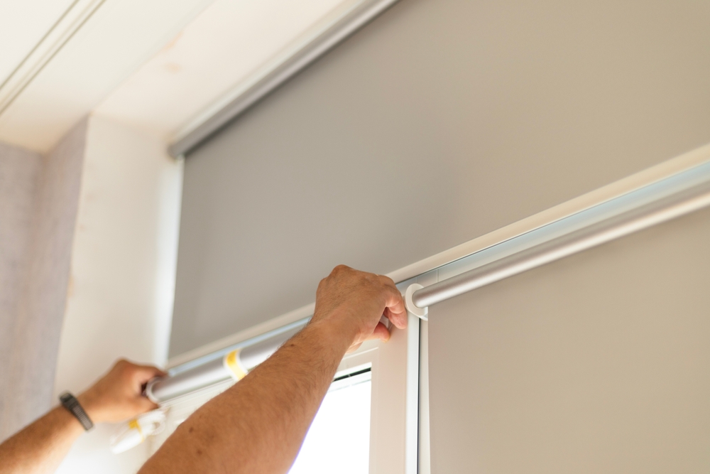 Hands installing window blinds on a window frame